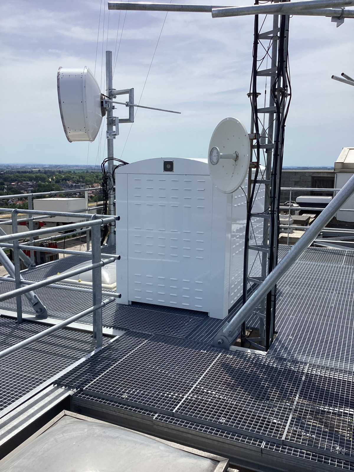 Roof-mounted telecommunications equipment canopy at Residentie 21, Koksijde, Belgium — source of structure-borne vibration transmitted into the penthouse